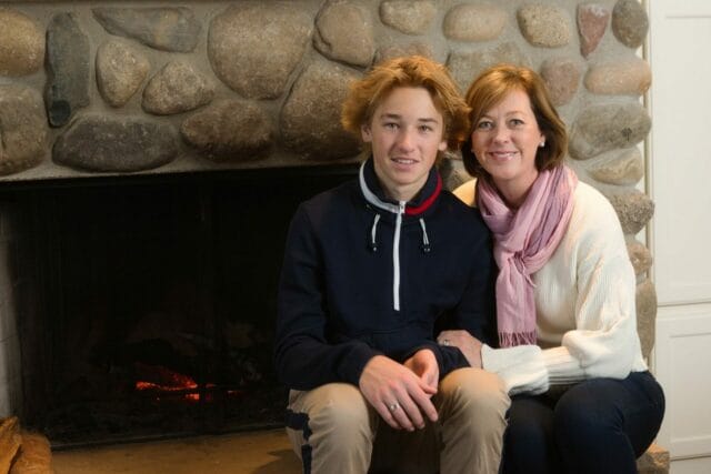 Mother and teenage son sitting near fireplace