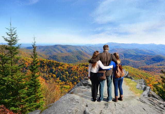 Father with his family looking at colorful fall hills and mountains. North Carolina, USA.